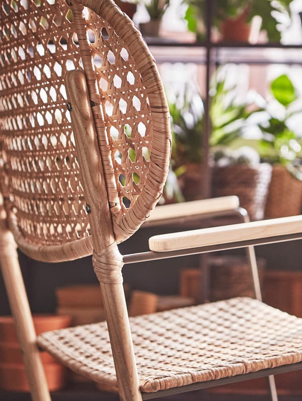 An IKEA GRÖNADAL rocking chair is situated next to a few pot plants.