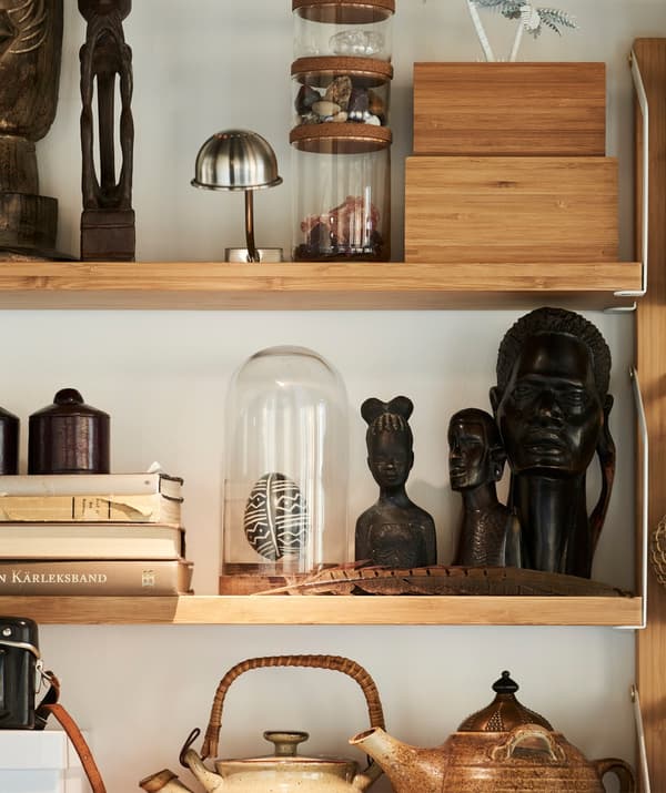 An IKEA HÄRLIGA glass dome on a shelf surrounded by a collection of souvenirs.