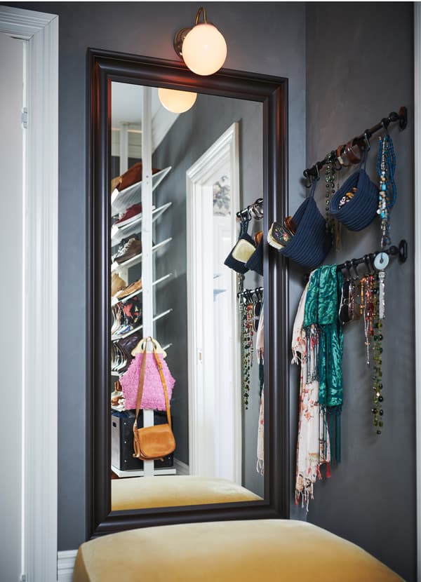 An IKEA HEMNES full-length mirror with a traditional styled black brown frame crafted from solid wood, in a walk-in closet.