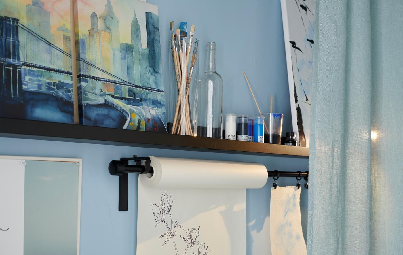 An IKEA MOSSLANDA black picture ledge with brushes, jars and art on show.