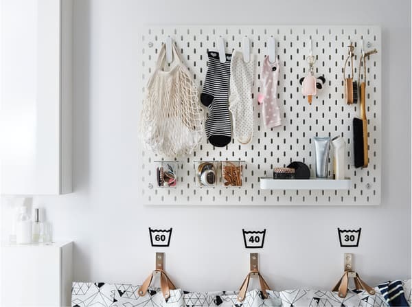 An IKEA SKÅDIS white pegboard used to hang lost socks and other household accessories in a laundry room.