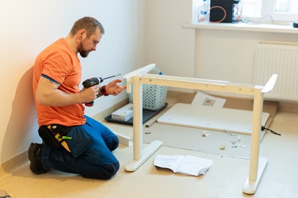 An IKEA volunteer assembles a bed in a bright room.