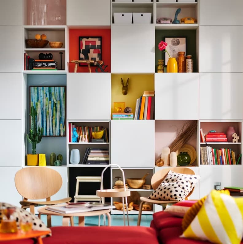 An image of a living room with a large bookcase behind a sofa filled with furnishings.