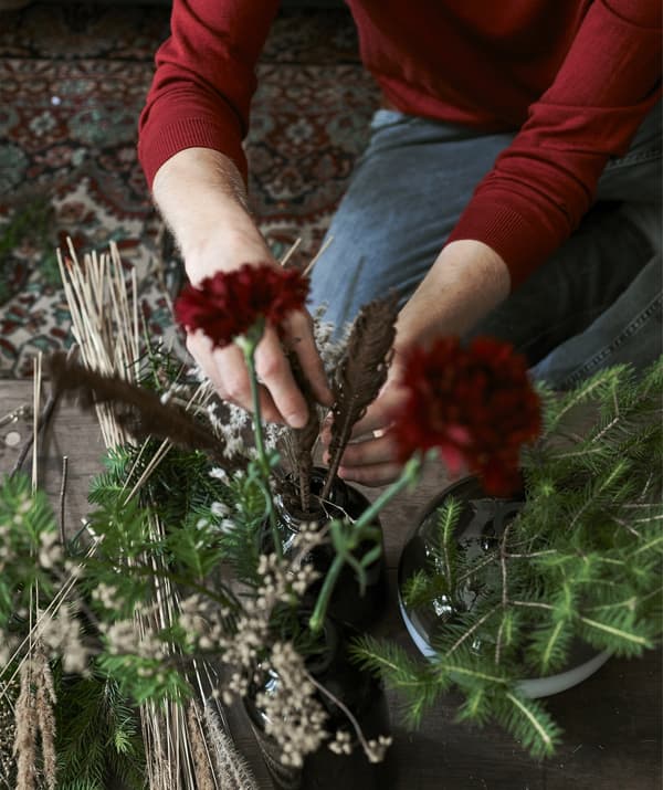 An image of Łukasz arranging flowers and sprigs in a vase.