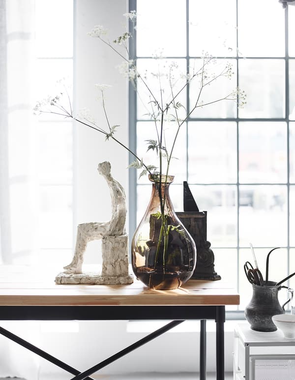 An industrial style table softened by personal objects and a vase with delicate flowers.