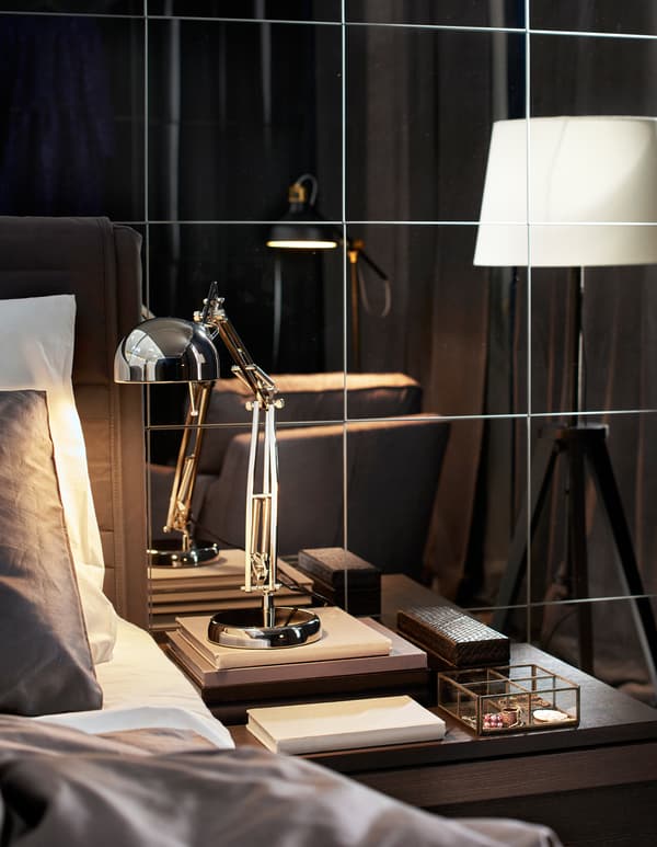 An industrial style work lamp as a bedside lamp with floor lamps in the background.