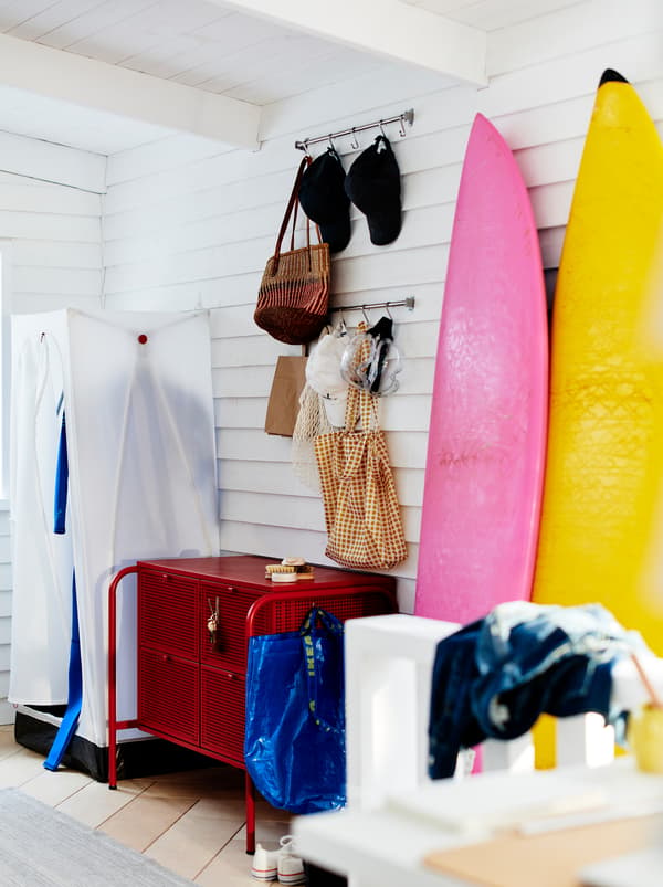 An informal hallway with a white VUKU wardrobe made from steel, fabric and plastic and a red NIKKEBY chest of drawers.