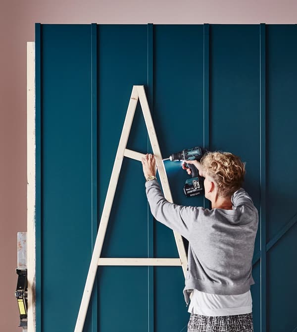 An interior designer assembles a wooden DIY Christmas tree.
