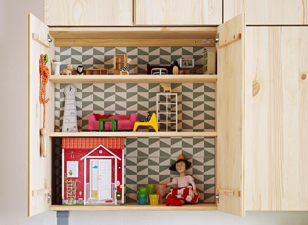 An IVAR cabinet placed low on a wall so a child can use it as a doll’s house.