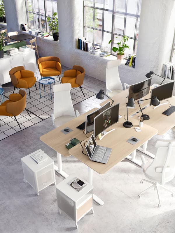 An office space with a cluster of BEKANT desks and a break out area with armchairs