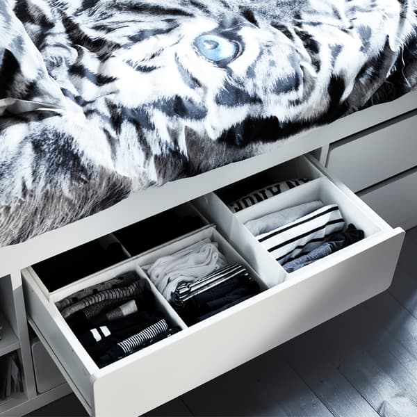 An open and organised drawer with clothes inside SLÄKT white bed frame with storage.