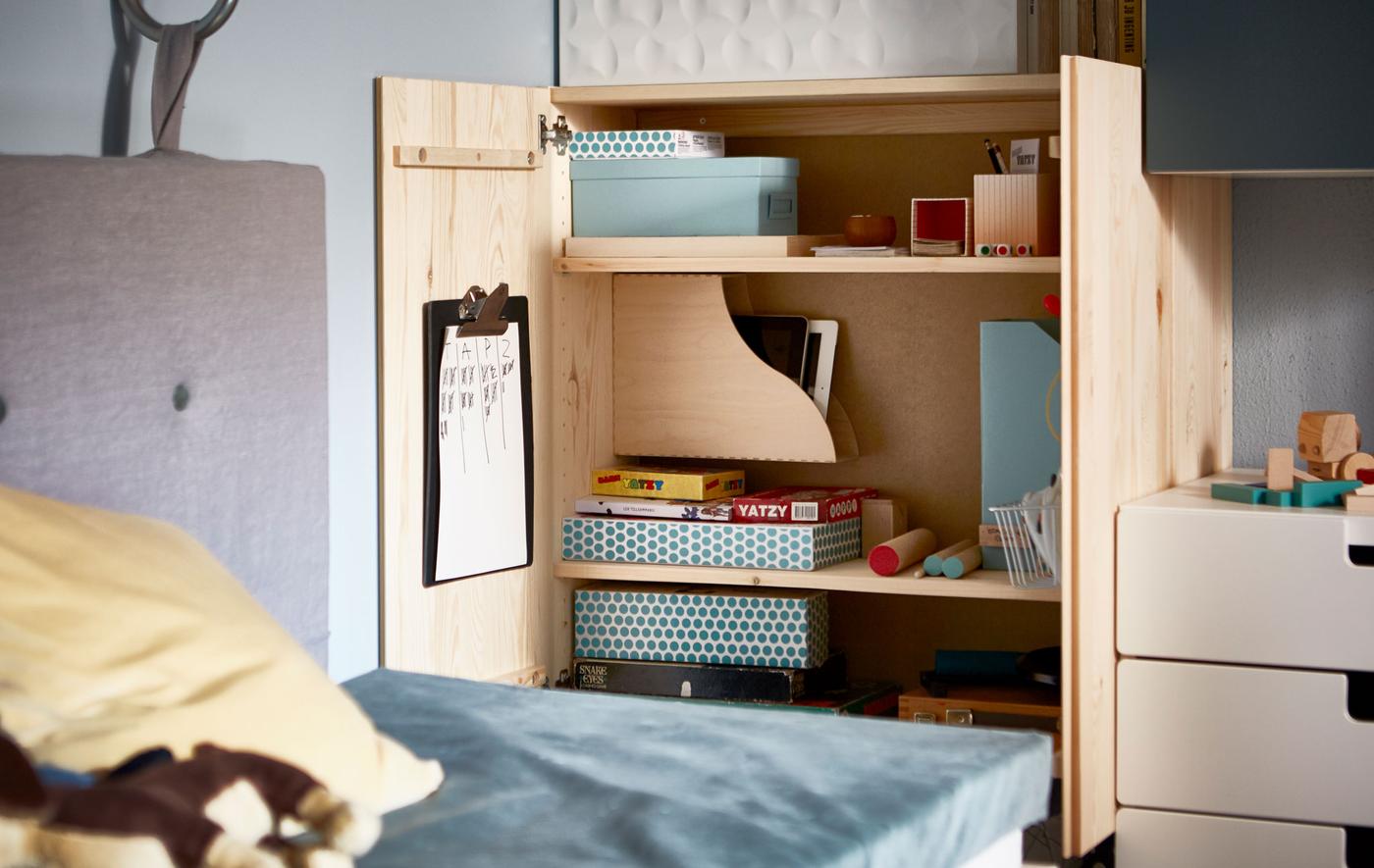 An open IVAR cabinet that’s organised with games in boxes and magazine files.