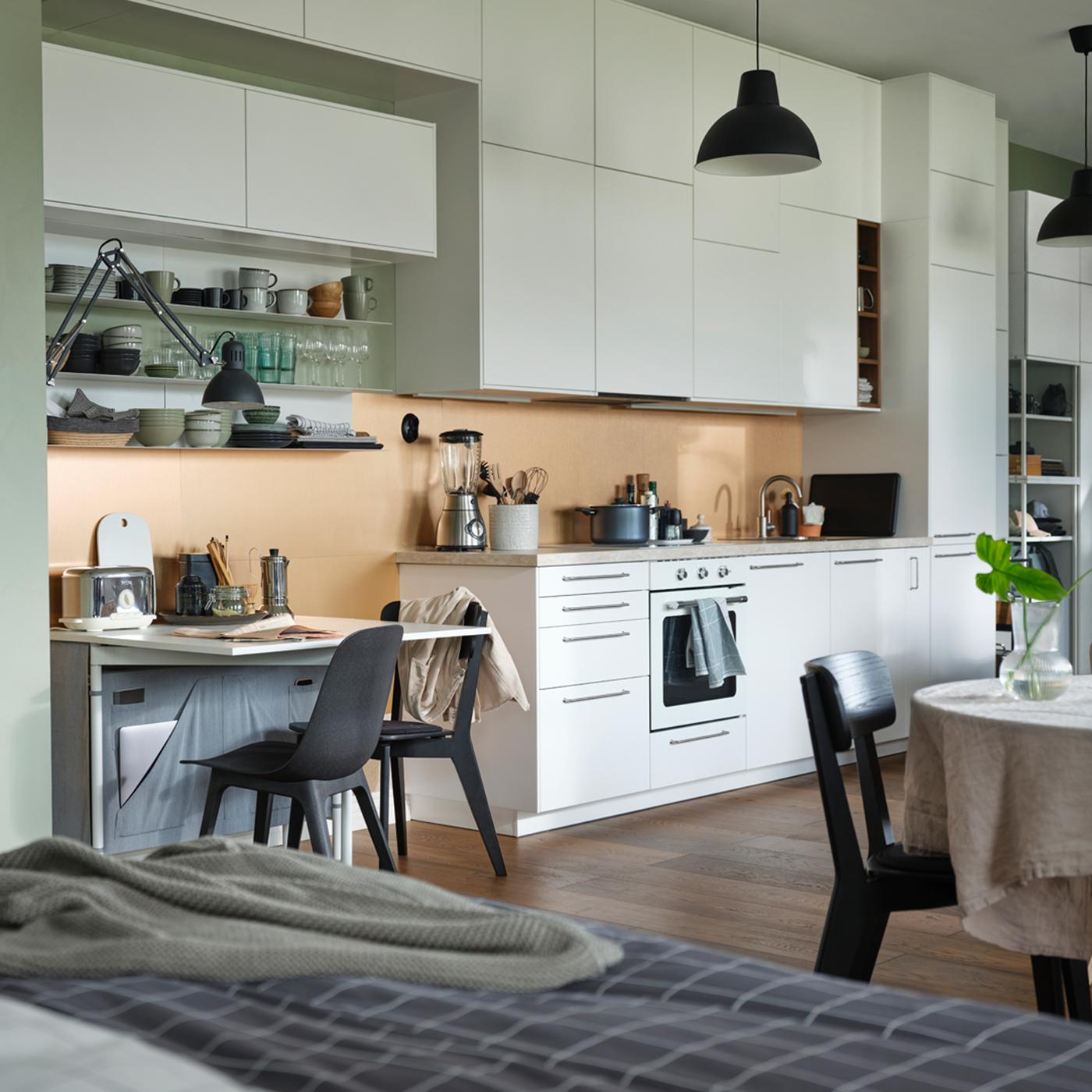 An open plan apartment with a KALLHÄLL gate leg table with storage and a white METOD kitchen with floor to ceiling cabinets.