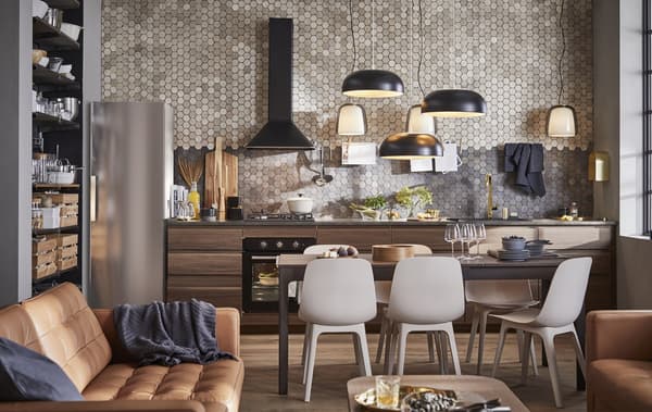 An open-plan kitchen, dining and living room with brown leather sofas and dark wooden kitchen cabinets against a tiled wall.