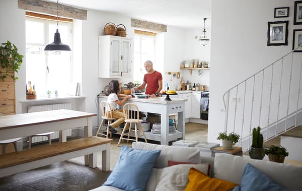 An open-plan living, dining and kitchen area, with white walls, white sofa and white kitchen.