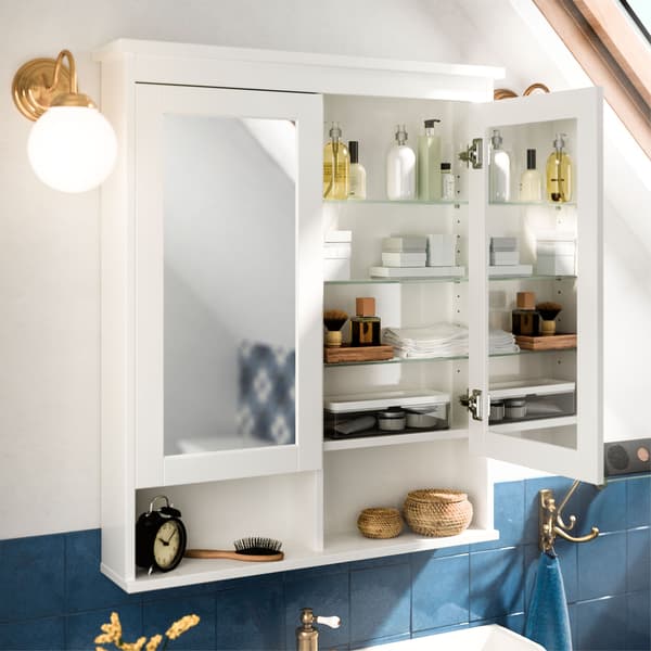 An opened IKEA HEMNES white mirror cabinet, revealing glass shelves, mirrors on both sides of the door and bathroom accessories.