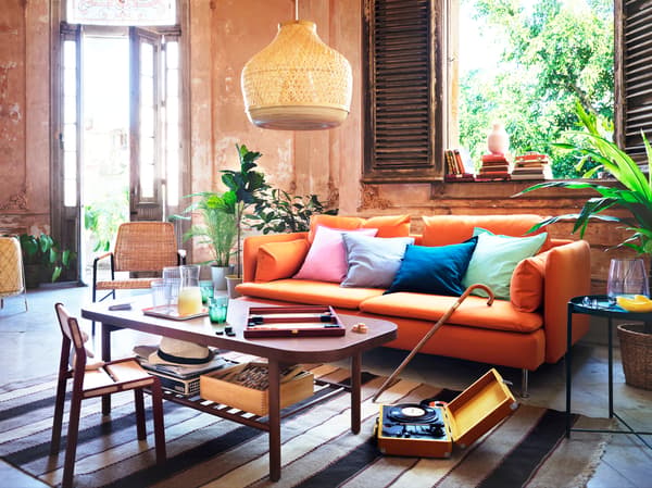 An orange sofa with various cushions, placed behind a dark brown coffee table.