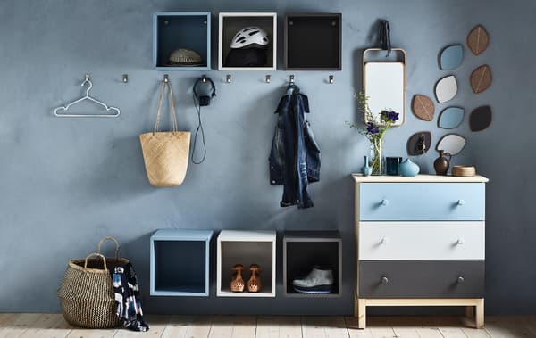 An organised hallway with hooks, different-coloured open IKEA EKET cabinets and a TARVA chest of drawers.