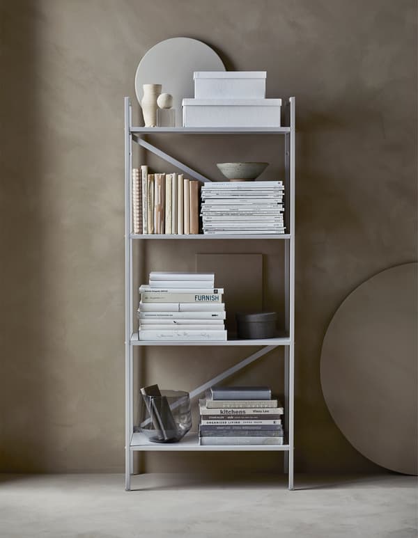 An organised, open shelving unit with storage boxes and books sorted by colours and covered in paper  
