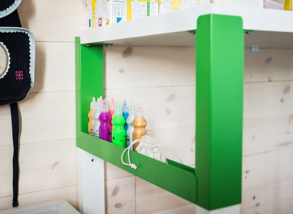 An organized study area for a child that uses a white and green PÅHL desk, a desk shelf unit and see-through boxes with lids to easily store small stuff.