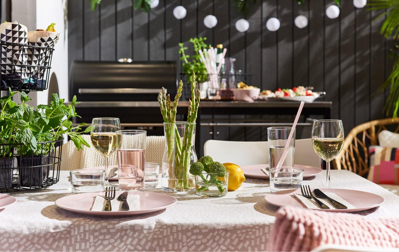 An outdoor dining table set with seasonal table settings and pink dishes and tablecloth