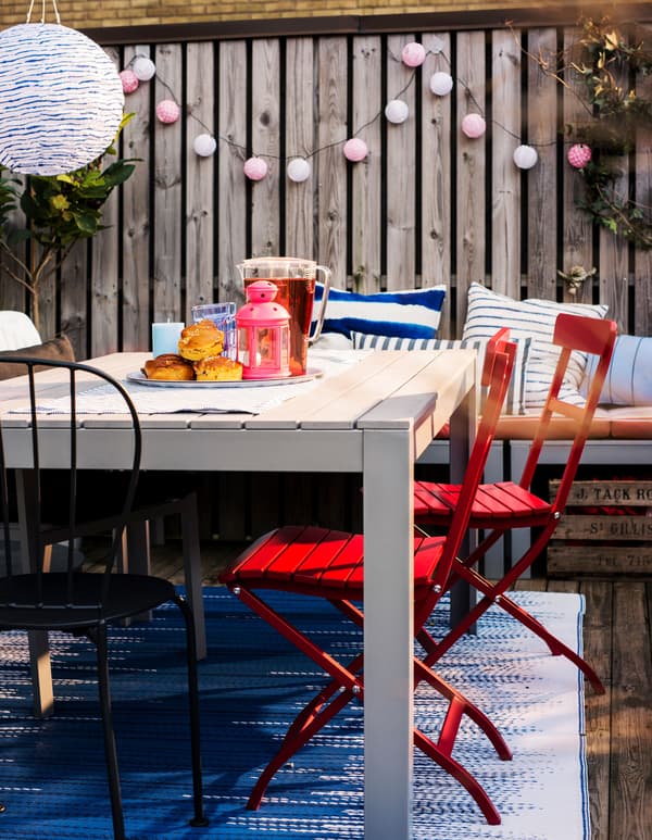 An outdoor dining table with a lantern, a plate of pastries, and juice.