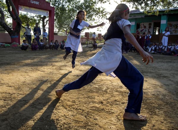 An outdoor evening scene in an Eastern country where girls are running around playing in the schoolyard.
