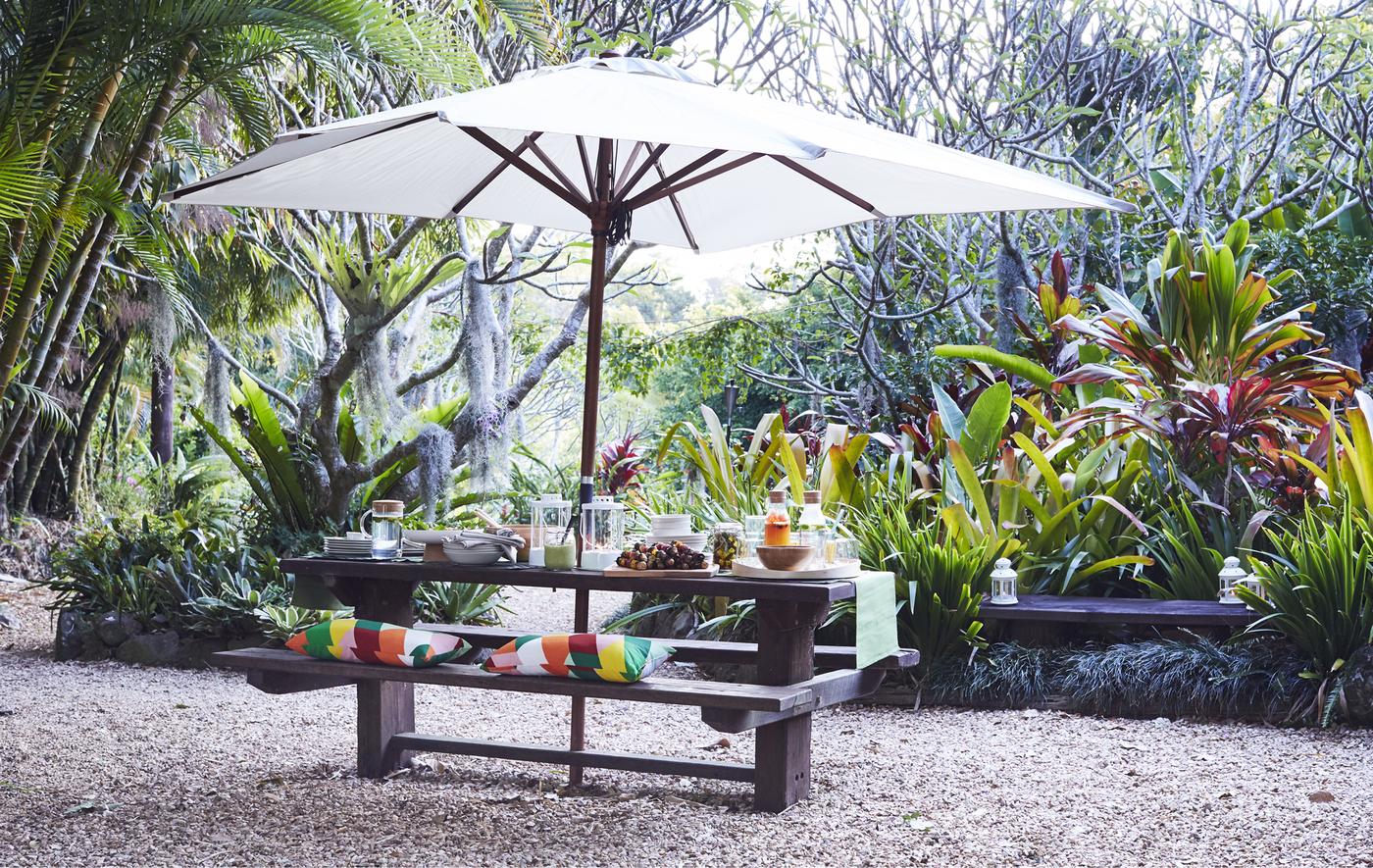 An outdoor table and bench with parasol.