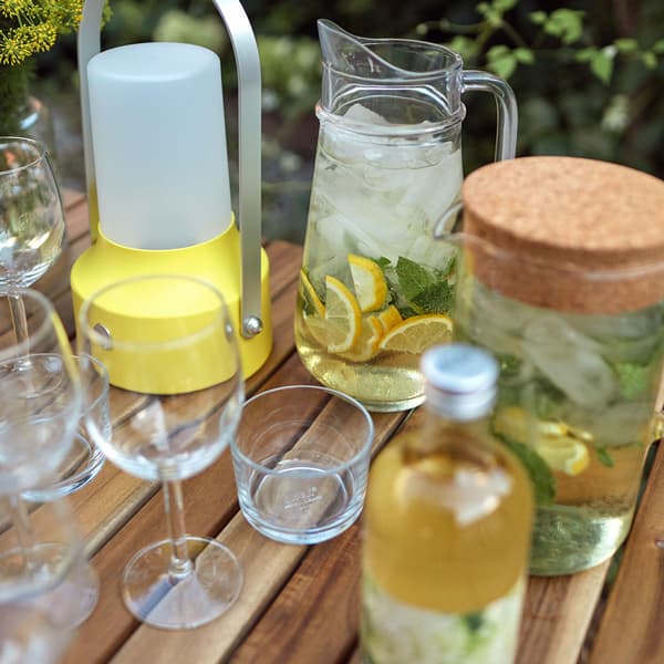 An outdoor table with wine glasses and lemon water in a pitcher.