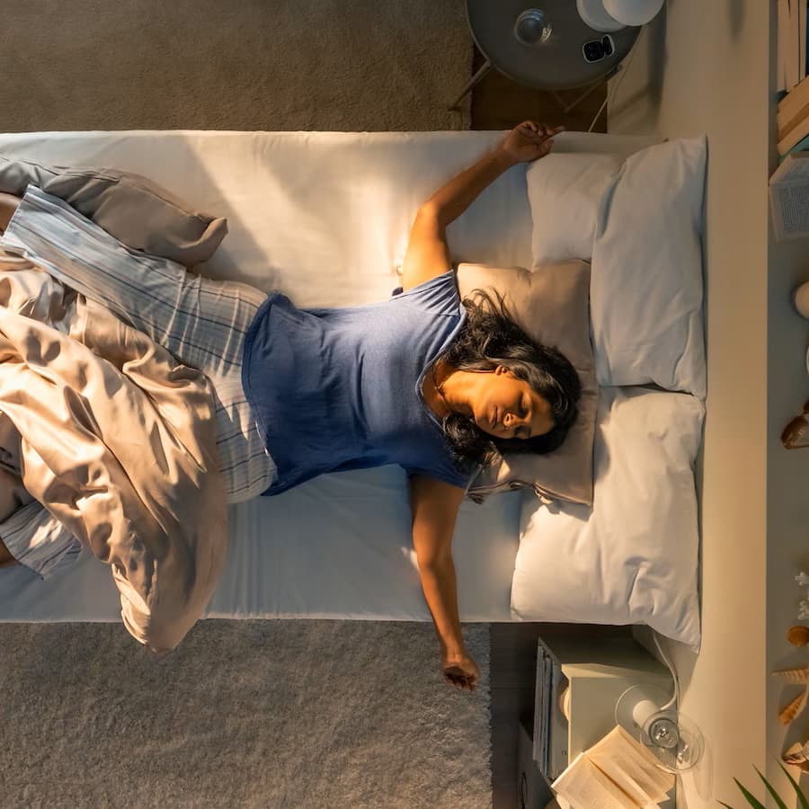 An overhead shot of a person sprawled out, sleeping in a bed