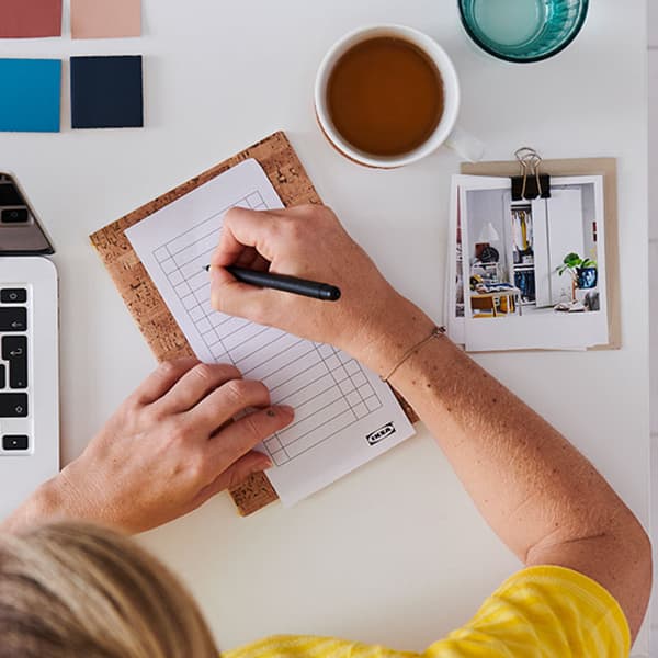 An overhead view of a person writing on a note pad.