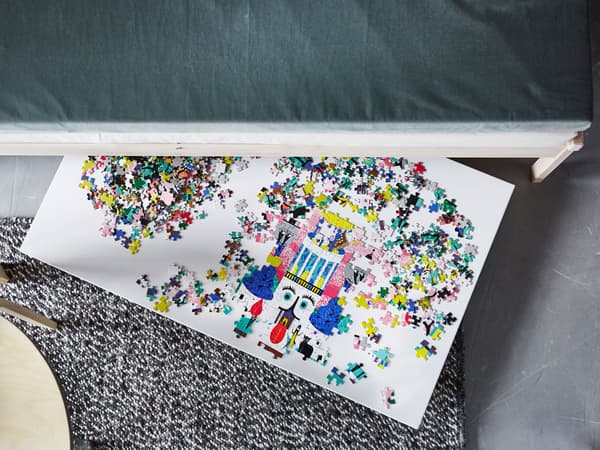 An overhead view of a puzzle on a board that’s sticking out from under a sofa