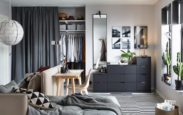 Anthracite NORDLI chest of 9-drawers against a back wall in a small living space with a sofa bed and desk.