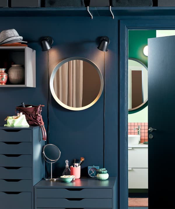 Area outside a bathroom, arranged as a simplified version of a make-up station: mirrors, chests of drawers, make-up items.