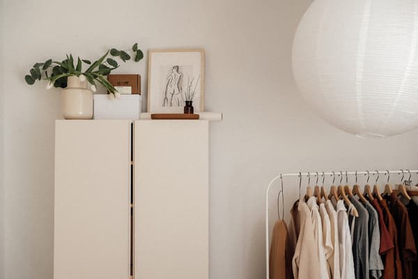 Armoire blanche et porte-vêtements MULIG blanc, tenant des vêtements de couleur neutre sur des cintres.