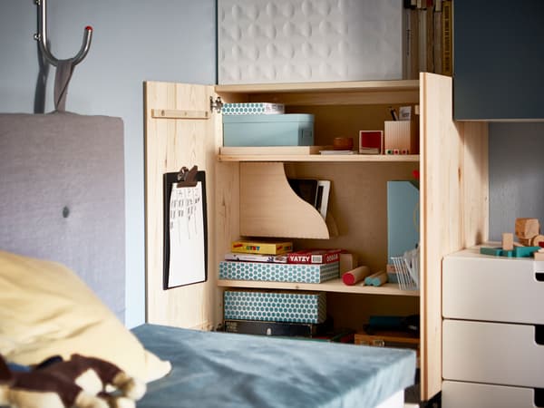Armoire IVAR ouverte, organisée avec des boîtes et des range-revues contenant des jeux 