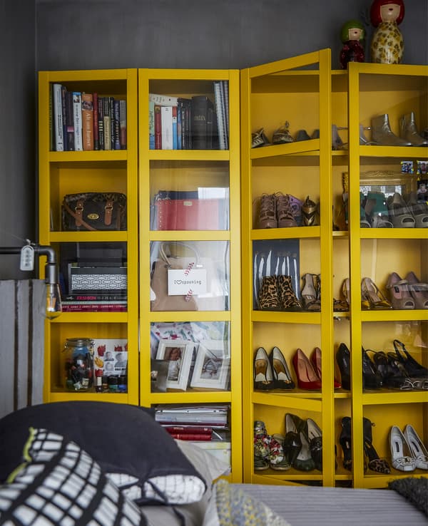 Armoire jaune révélant des chaussures et des livres.