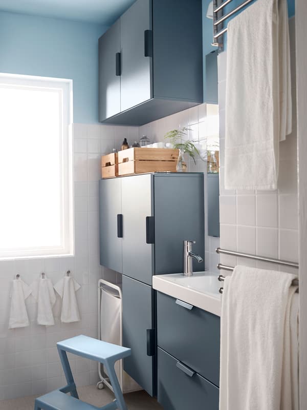 Armoires de salle de bain bleues occupant tout l’espace, du sol au plafond pour maximiser le rangement.