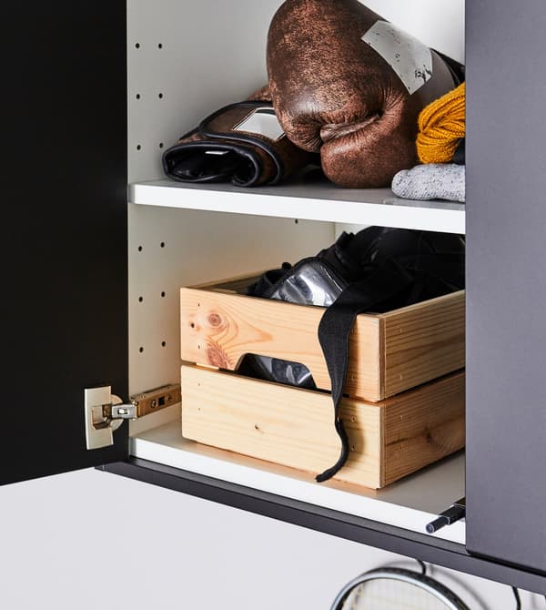 Armoires grises avec deux portes ouvertes montrant deux étagères blanches avec gants et équipement de boxe dans une boîte en pin.