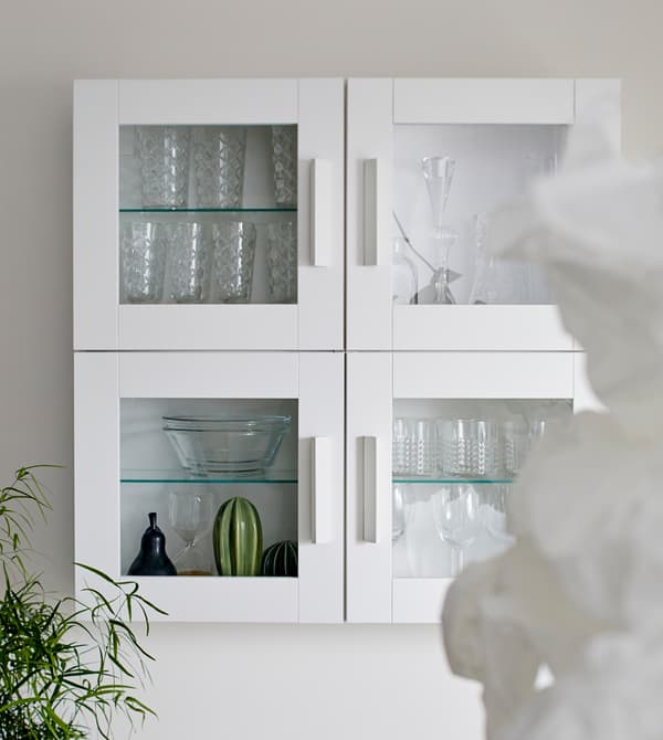 Armoires murales blanches avec portes en verre, pour le rangement des verres.