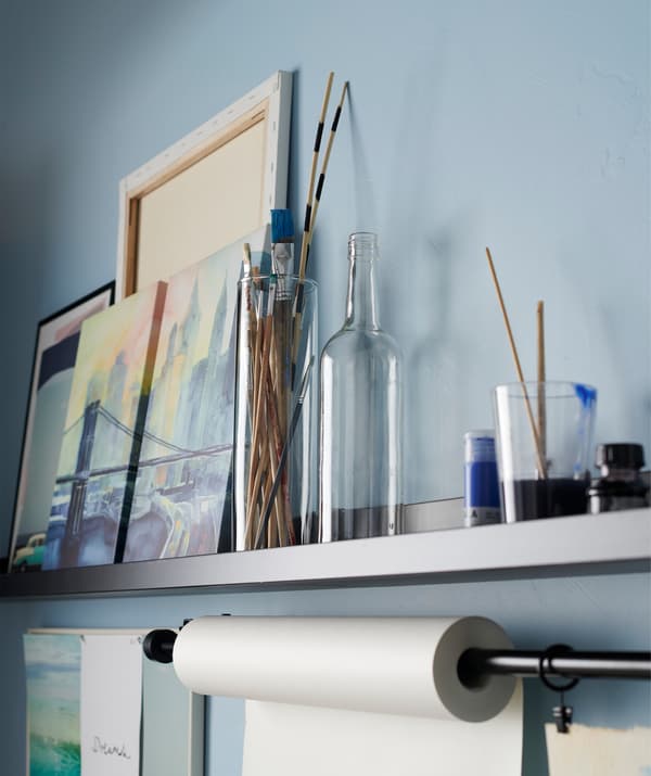 Art projects and brushes displayed on a black MOSSLANDA picture ledge