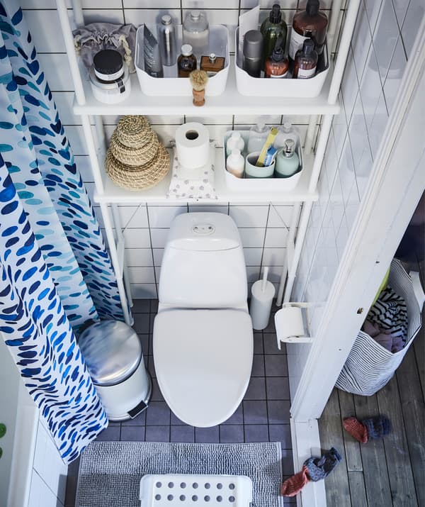 Articles de toilette disposés sur des étagères de rangement installées au-dessus des toilettes.