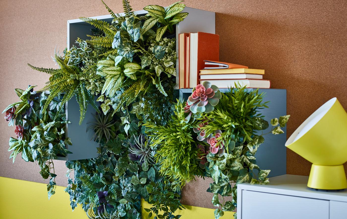 Artificial green potted plants used to create wall décor in open storage boxes.
