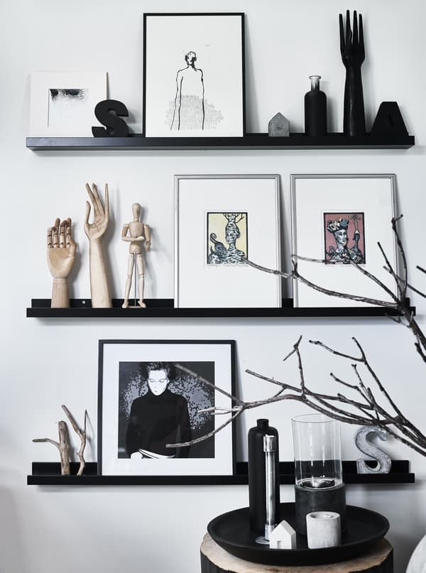 Artwork and objects displayed on black picture rails.