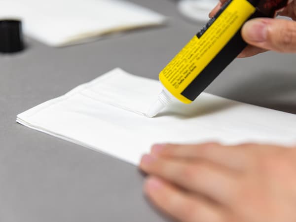 Auf die Papiertüten wird Kleber in einer T Form aufgetragen. Die Tüten werden zusammengeklebt.