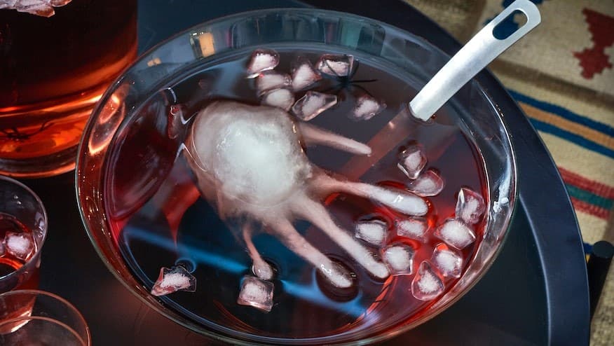Auf diesem Bild kann man eine Halloween Bowle sehen mit roter Flüssigkeit in der eine Hand aus Eis schwimmt.