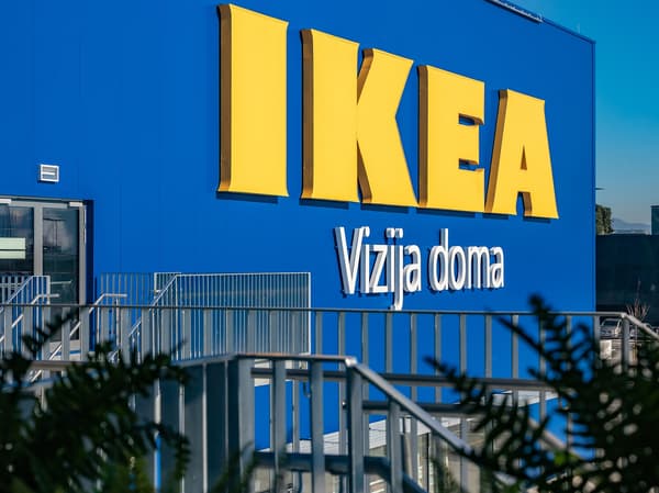 Avtomobili so parkirani v vrsti pred pokritim vhodom trgovine IKEA. 
