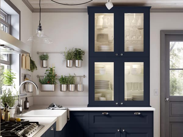 AXSTAD blue glass cabinet with lighting inside and a window to the left.