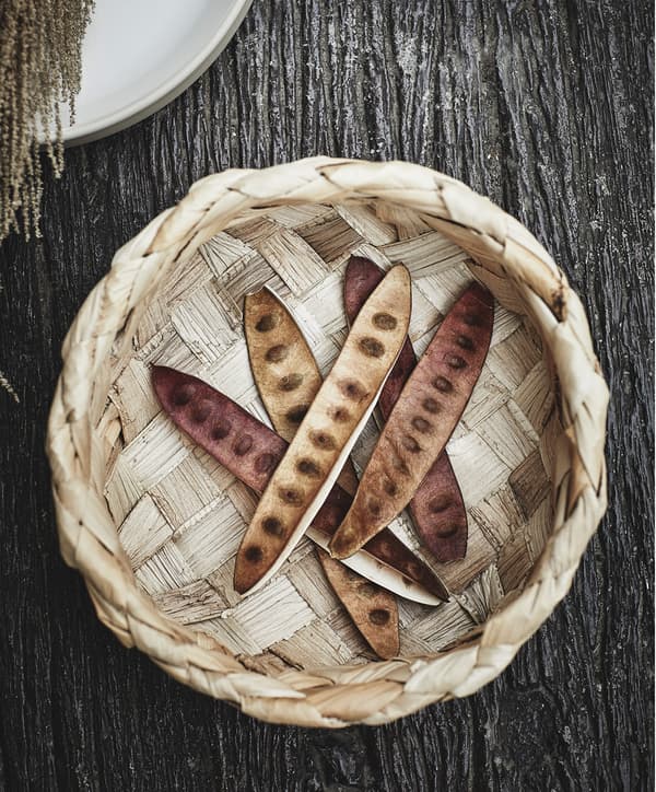 Bakul HANTVERK IKEA dibuat daripada serat pisang kelihatan dari atas, dengan beberapa lengai kacang pea eksotik berwarna coklat berada di dalamnya.