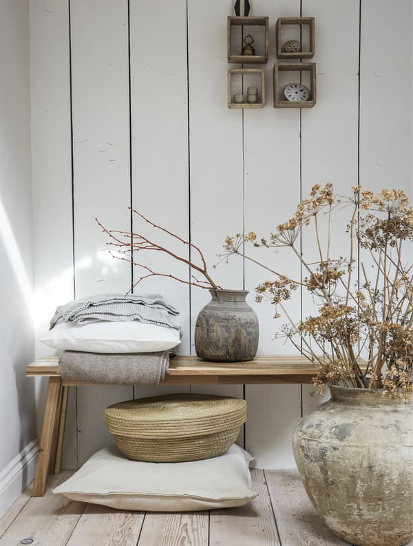 Banc en bois avec pots rustiques, feuilles séchées et textures naturelles.